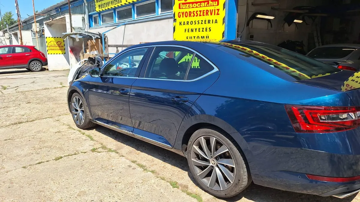 Az újrafényezett, kék metál Škoda Superb oldala a Luzso Car műhelye előtt