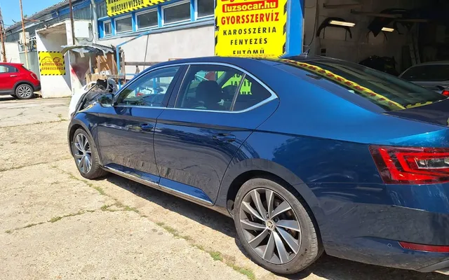 Az újrafényezett, kék metál Škoda Superb oldala a Luzso Car műhelye előtt