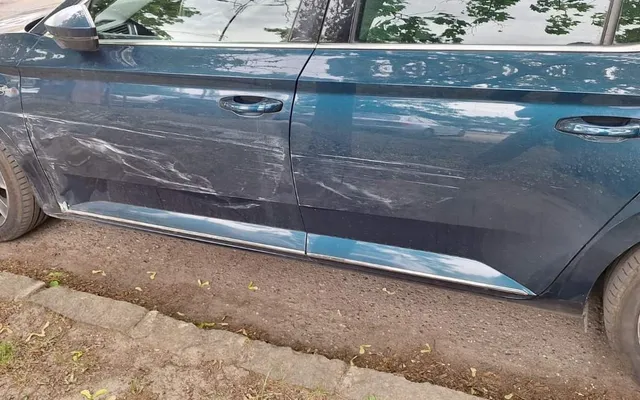 Koccanás nyoma egy Škoda Superb oldalán: végigkarcolt ajtók és küszöb, az utcán fényképezve